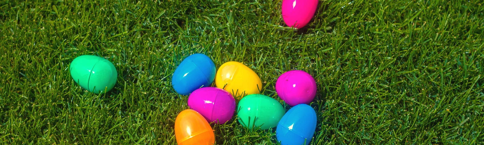 Plastic eggs of various colors resting on the grassy ground.