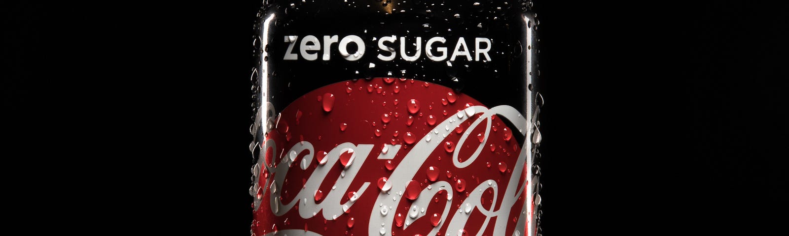 A can of Coca-Cola Zero Sugar (red, white, and black) stands in front of a black background.