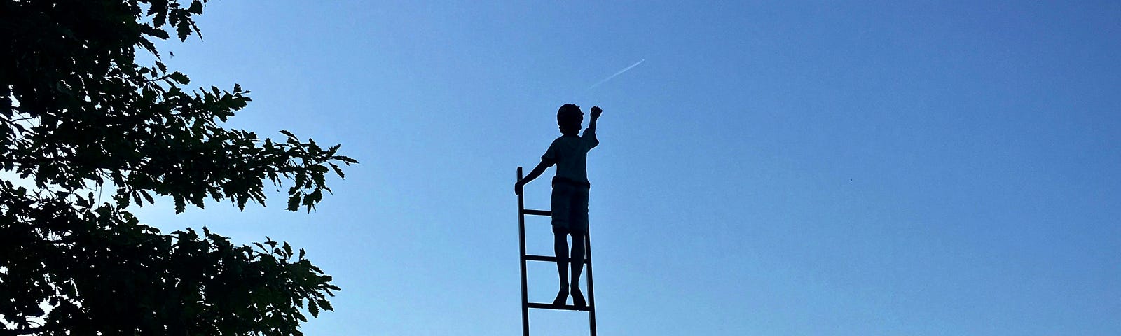 An iron statue of a child at the top of a ladder in a lake landscape