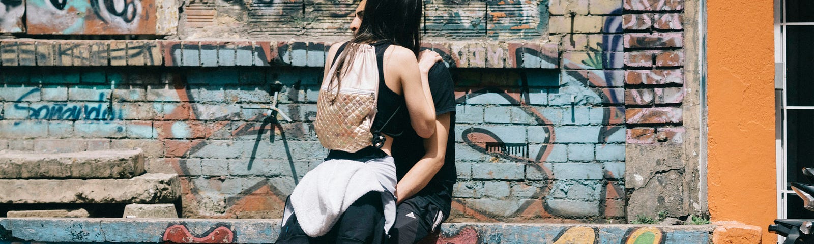 Young teenage couple hugging against a graffiti covered wall