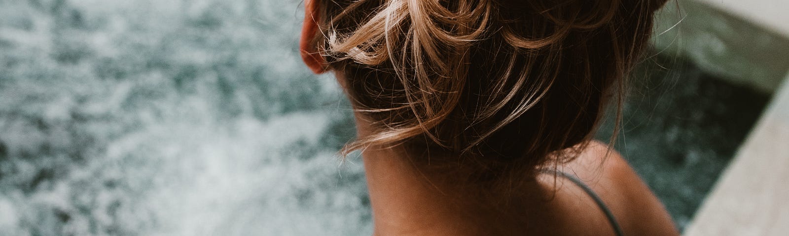 A woman is seen in close-up, sitting in the bubbling water of a square hot tub. Hot tubs have become synonymous with relaxation and indulgence. They offer a luxurious retreat from the stresses of everyday life. While these heated havens may seem like the epitome of comfort, it is crucial to be aware of their potential health hazards.