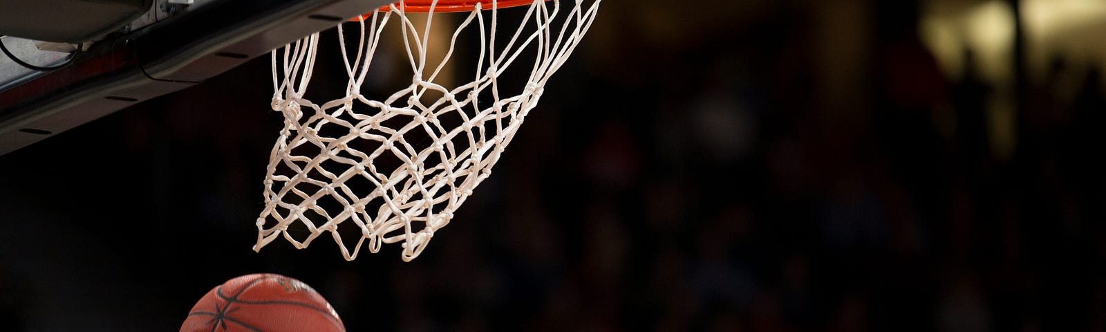 Basketball in midair, just dropping from the net. Black background.