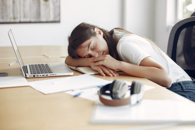 Exhausted blogger taking a nap next to laptop