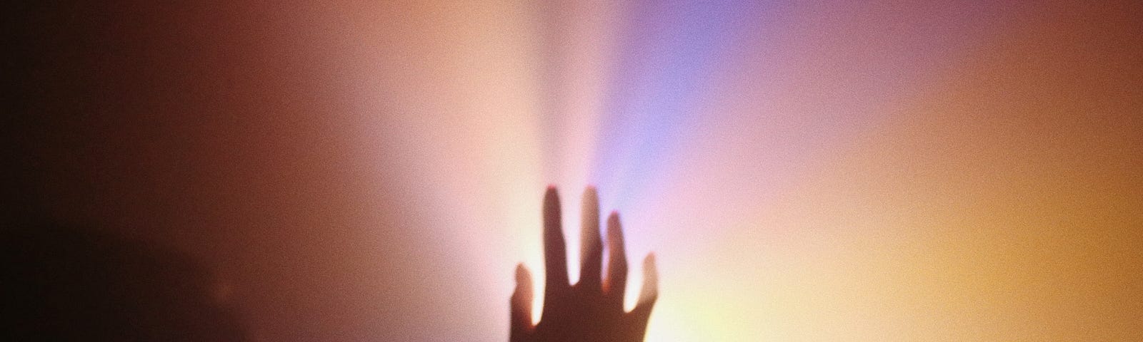 A hand reaching up to a colorful light.