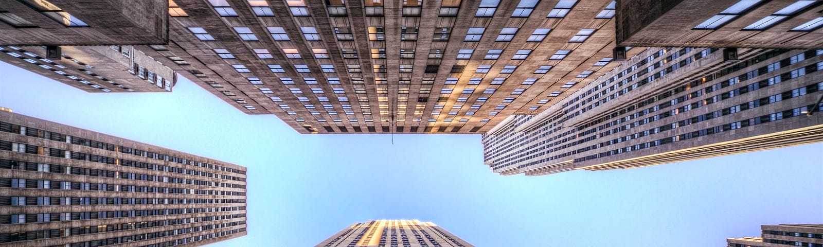 At the bottom of skyscrapers, looking up into the blue sky.