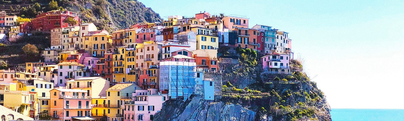 Beautiful Mediterranean coast with sun shining and various brightly colored buildings in background.