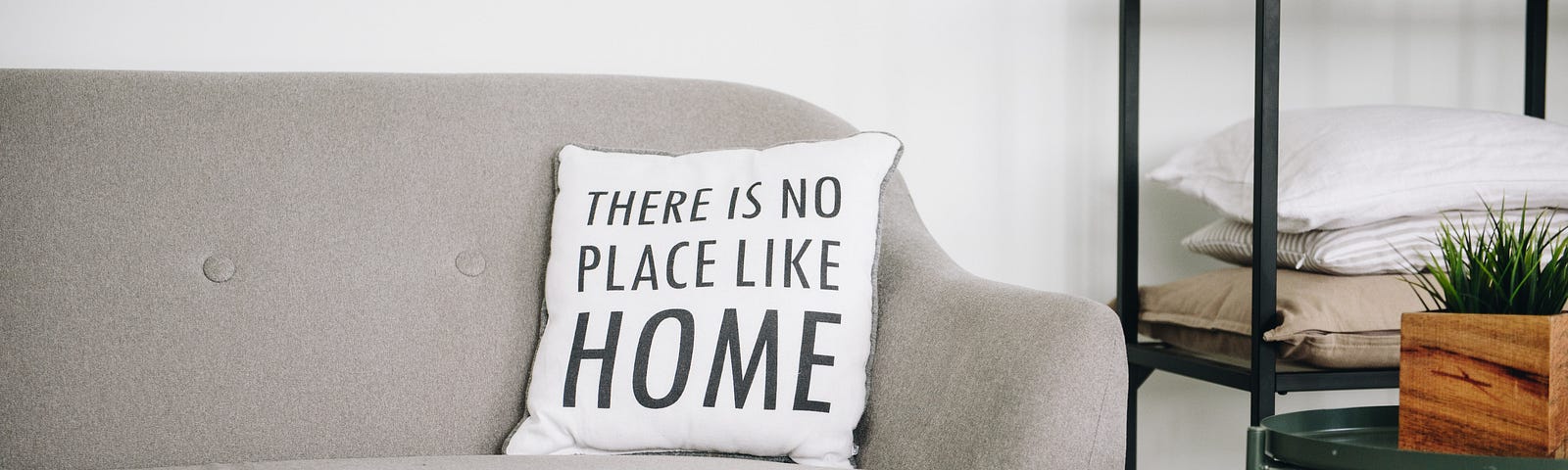 A sofa at home with a cushion that says “There is no place like home.”