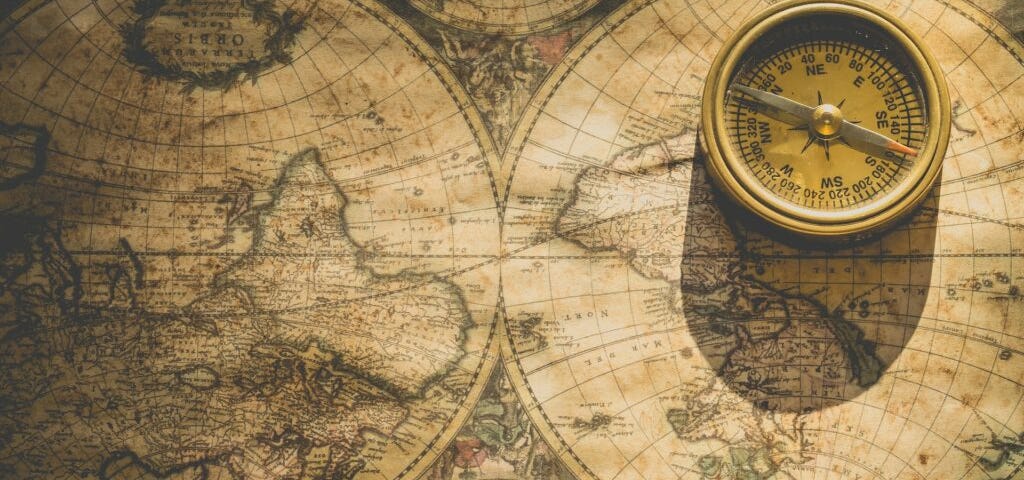 An old map with a compass in the top right corner. Image courtesy of Ylanite Koppens at Pexels.