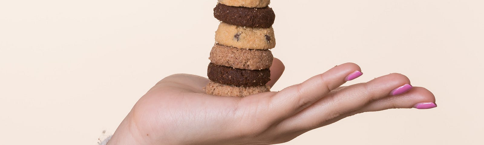 A hand displaying a stack of cookies of various types.