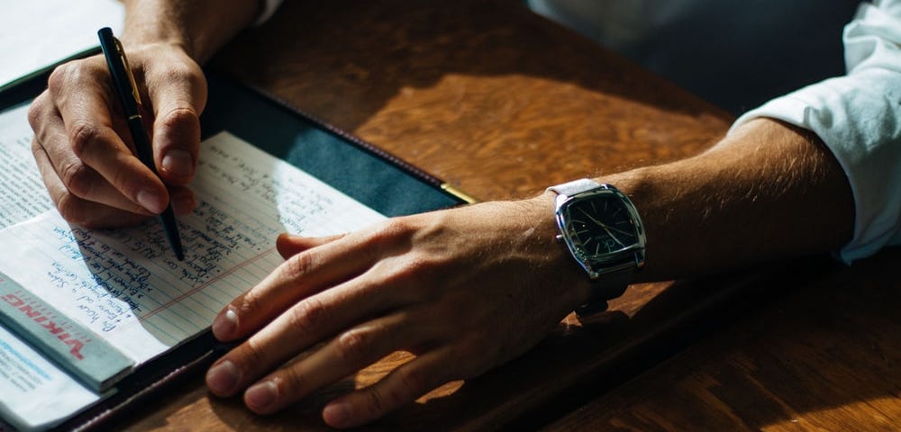 A men writing a pitch on paper.