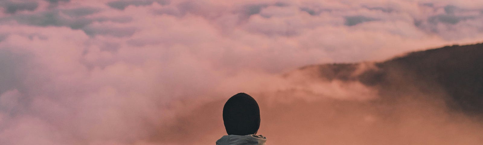 Man on the edge of a cliff overlooking a sea of clouds.