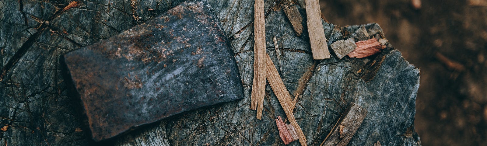 A worn axe lying on a chopping block surrounded by splinters.