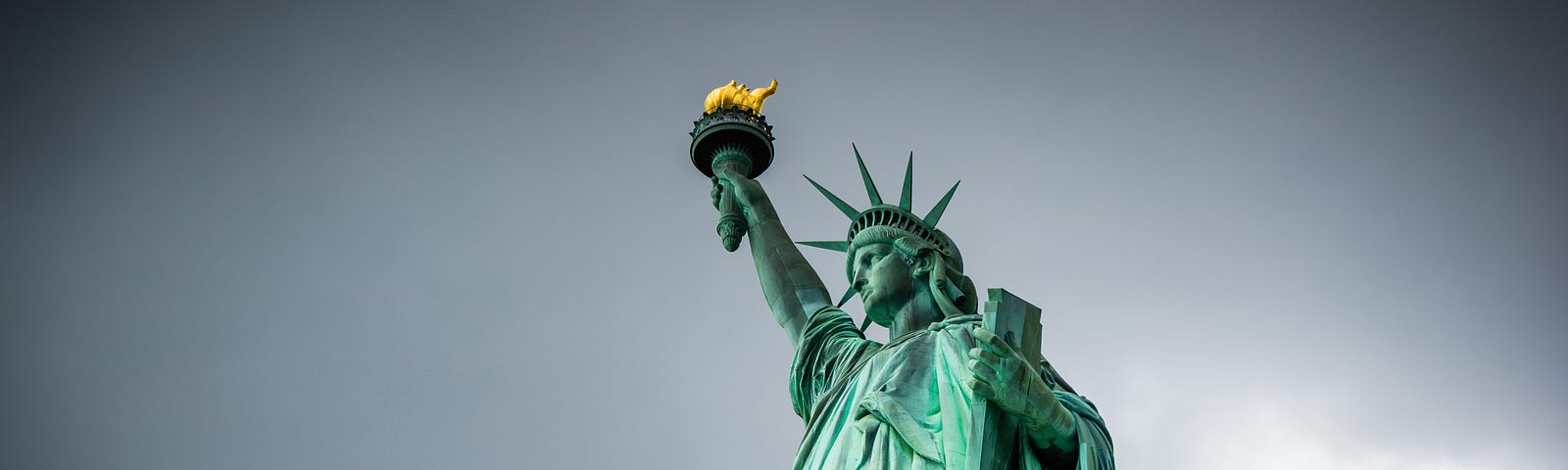 Photo of the Statue of Liberty by Jason Krieger, via Unsplash, against a grey backdrop