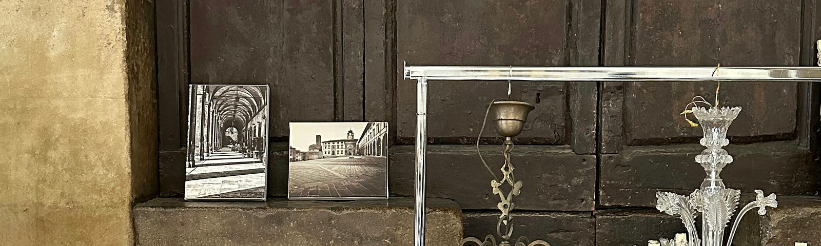 Antique candelabras, a dish and two photos sitting in front of a doorway.