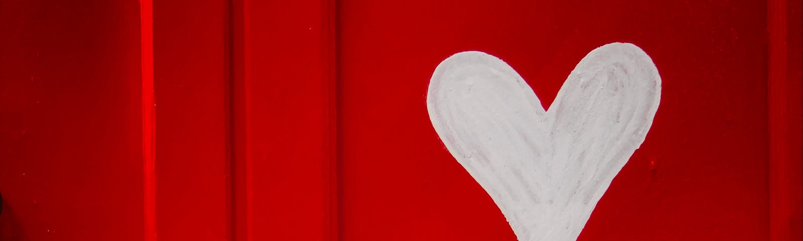 A bright red door with red, pink and white hearts painted on it.