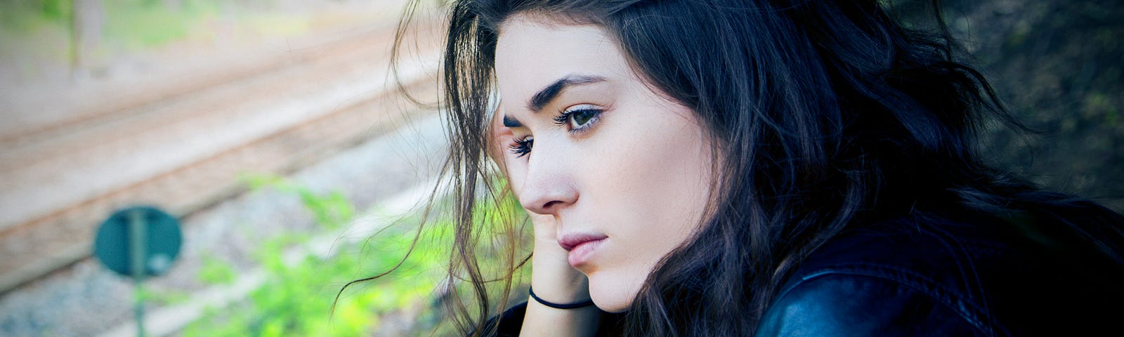 Sad girl looking down on rail track