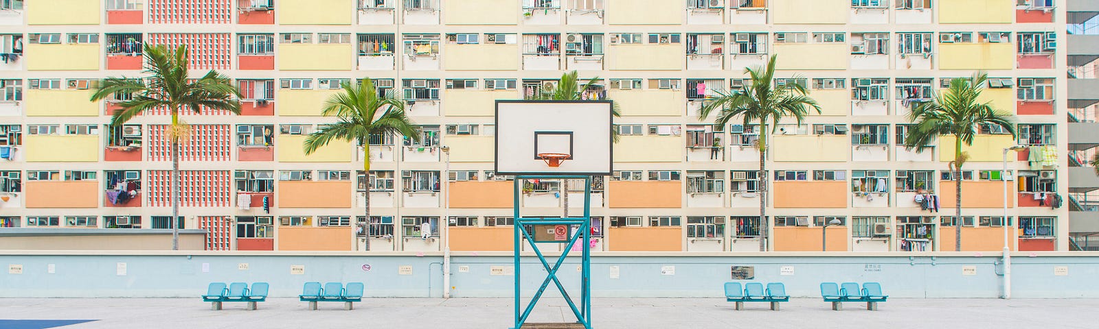 An empty basketball court with a big apartment block behind it