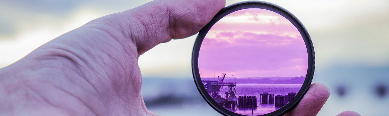 A purple-colored lens in hand shows a harbor and the sea.