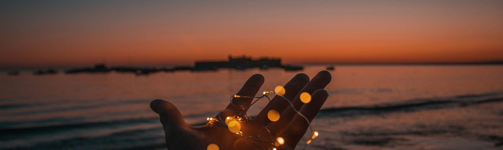 A pair of hands holding a bunch of little orange led lights.