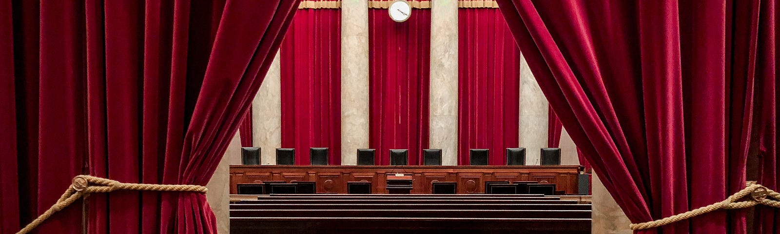 a view of the vacant chairs on the supreme court of US with red drapes