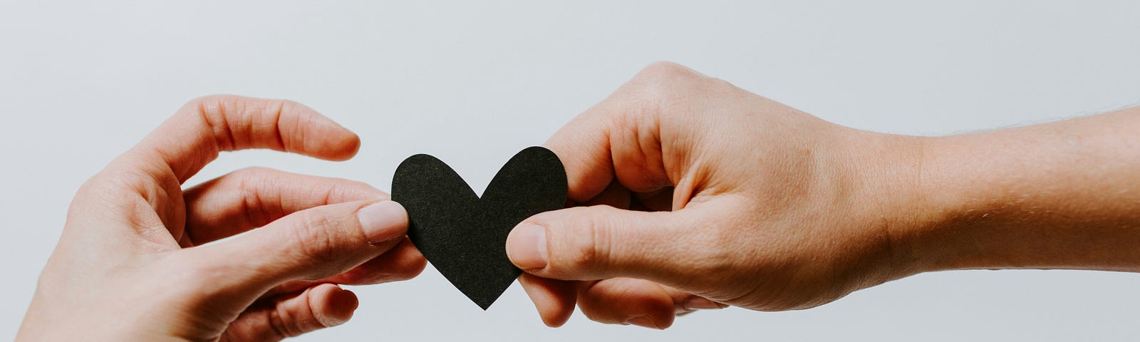 A person’s hand offering a heart to another person’s hand