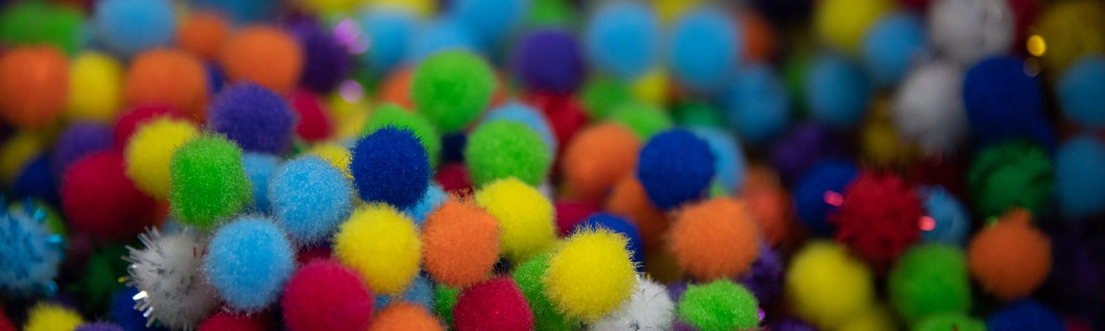 little fuzzy balls of many colors, including blue, turquoise, red, pink, white, yellow, and green