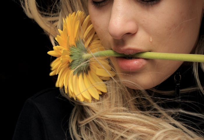 Tearful young woman with a flower in her mouth