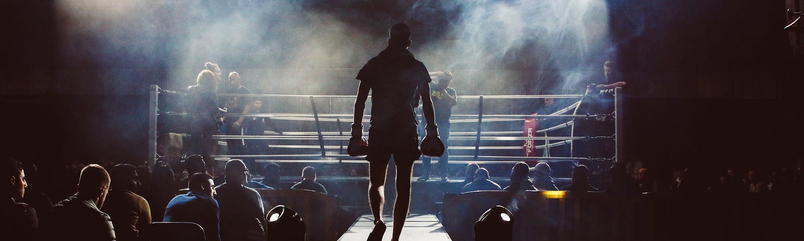 A boxer walks away from us, towards the ring. People sit below the walkway on either side. Intermittent fasting (IF) involves dividing the day or week into periods of eating and fasting. The most common method is the 16/8 approach, where individuals fast for 16 hours and limit eating to an 8-hour window.