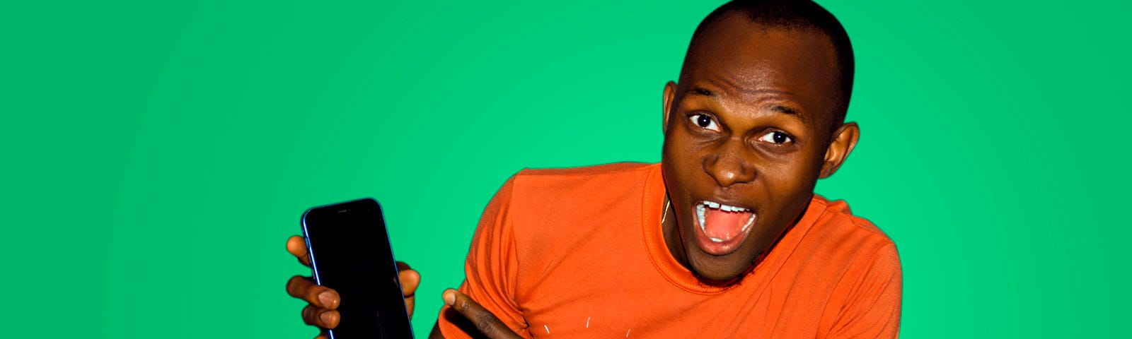 a black man in a red t shirt pointing at his phone.