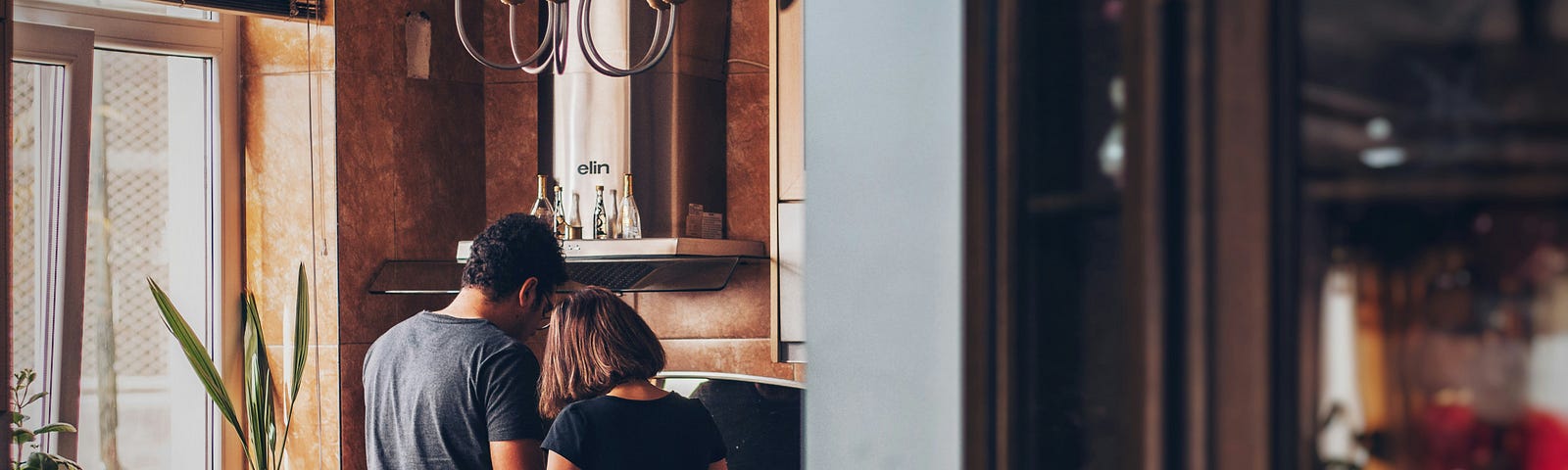 A back shot of a couple working together in their kitchen.