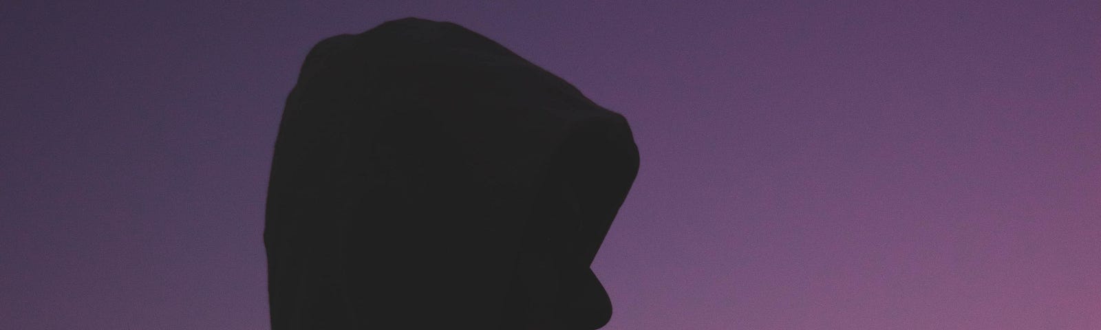A silhouette of someone looking sad against a sunset.
