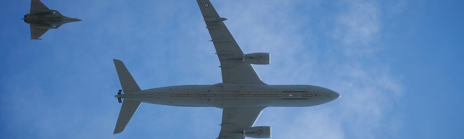 An airliner followed by two military jets, viewed from below