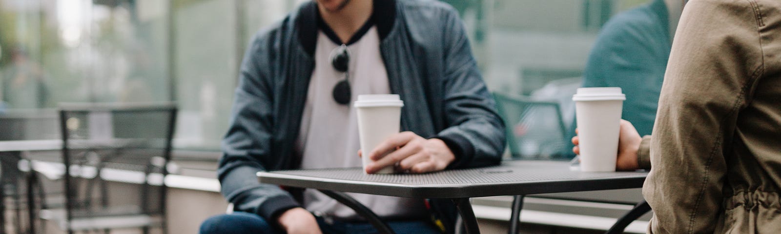 man and woman drinking coffee and looking at their pet corgi dog.