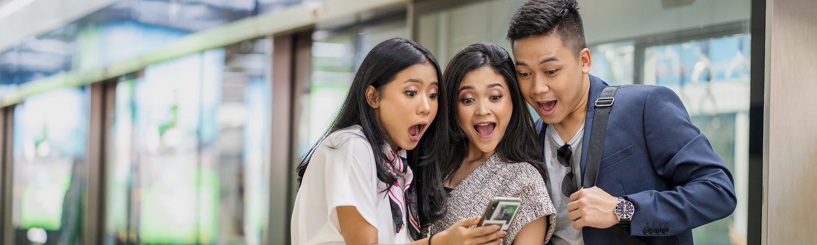 Three people staring with excitement at a phone.