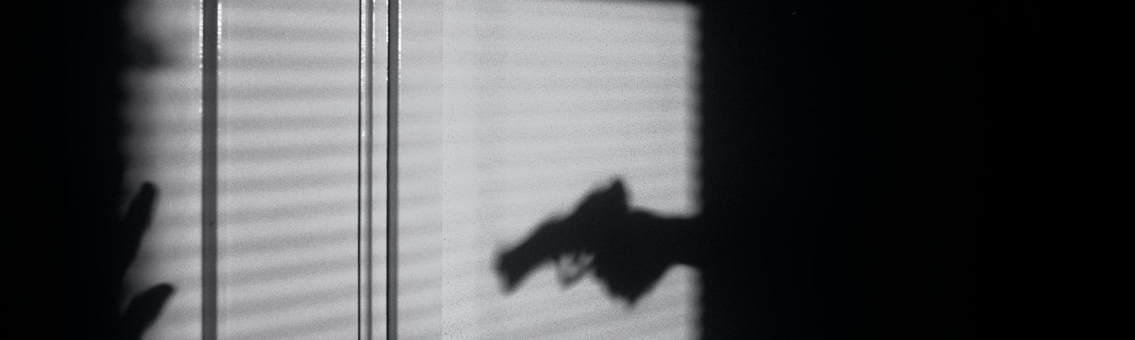 The shadow of a pistol pointing at a victim.