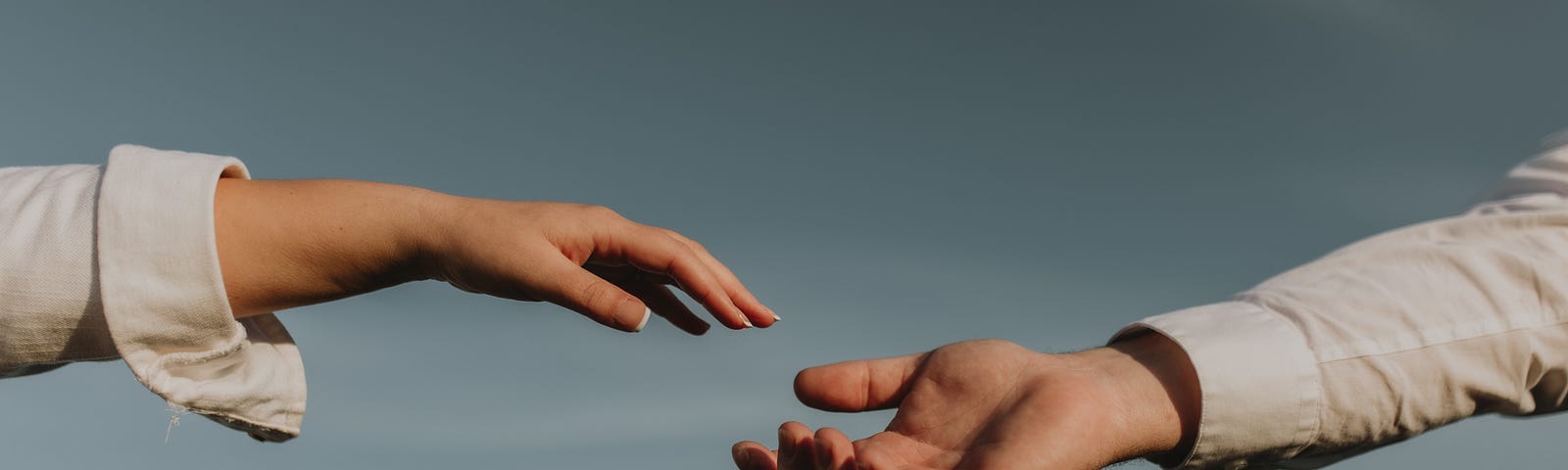 A hand reaching from the left toward an outstretched hand on the right