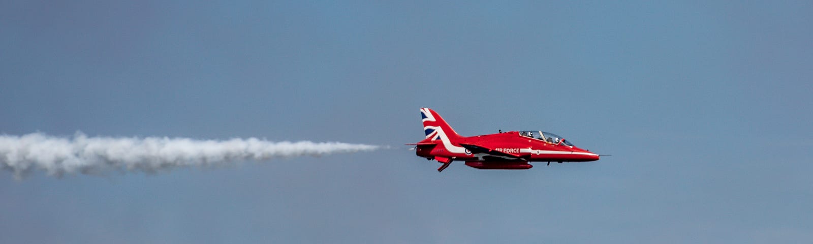 Red Arrow flying left to right, trailing white