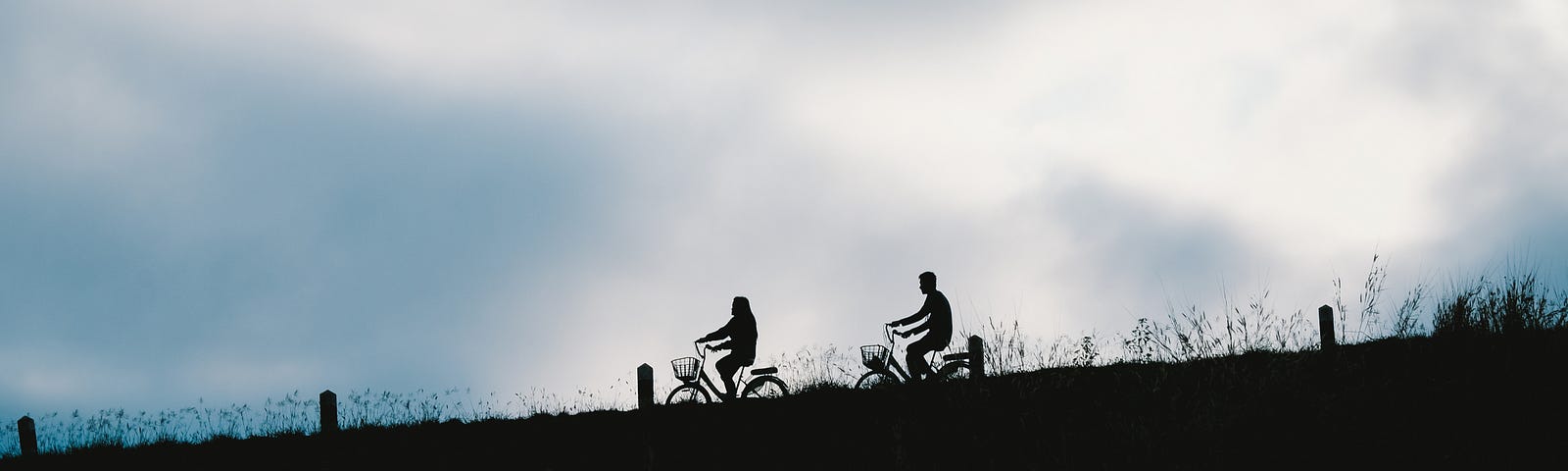 The silhouettes of two people riding bikes