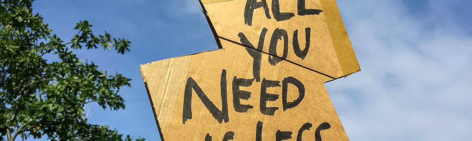 Sign on cardboard reading ‘all you need is less’.