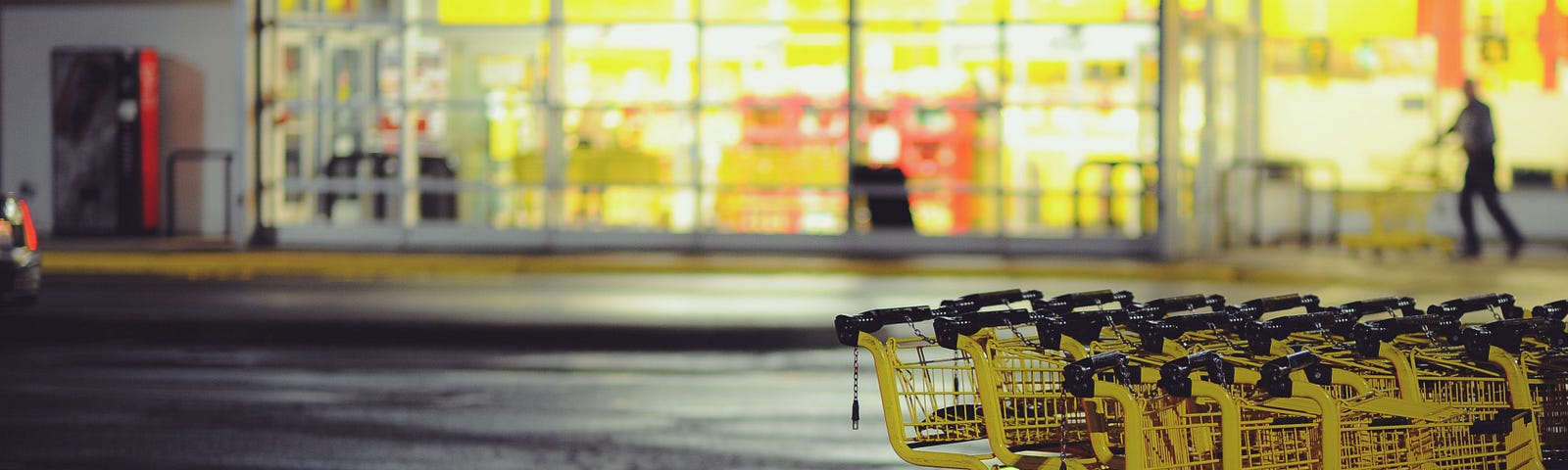 Two ros of yellow shopping carts sit in front of aa well-lit supermarket. Turns out, your trusty retail companion is not as clean as it seems. In this essay, we’ll explore the germ-laden world of shopping carts, unveiling findings from a 2012 study that exposed the true extent of microbial mayhem.