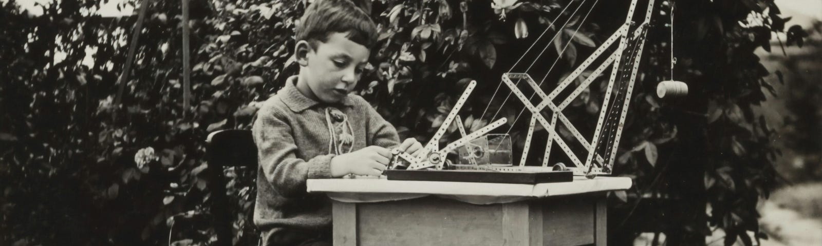Young boy playing with Mecano set: black and white