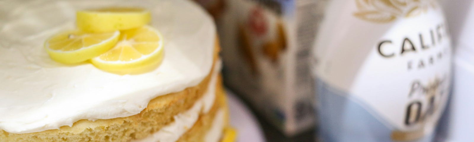 A lemon layer cake on a shelf in a fridge next to creamer