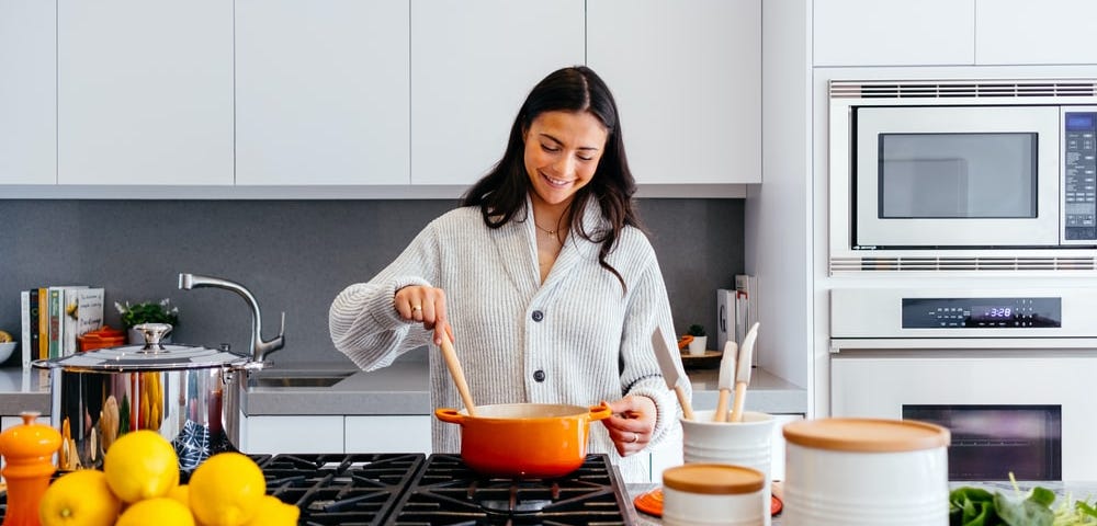 A woman is cooking while having a big smile on her face.