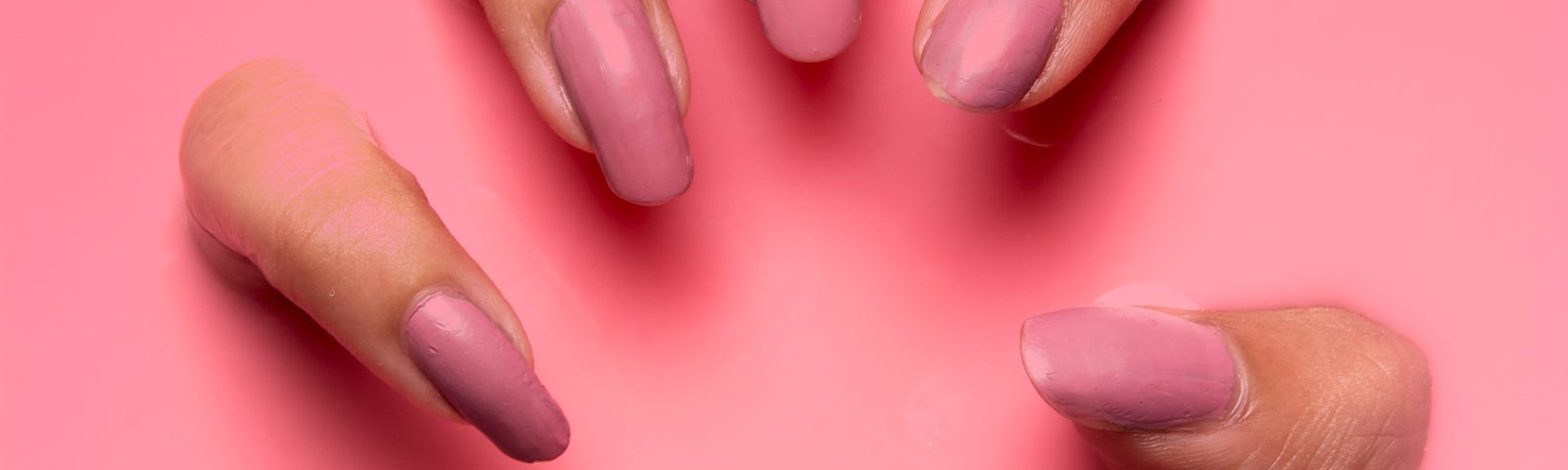 Horribly manicured hand with pink nail polish scratching out of a pink background.