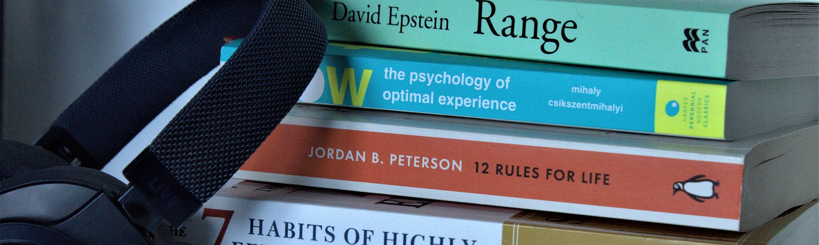 A picture of self-help books and a black headphone.