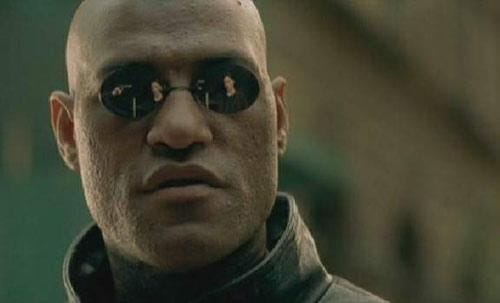 Morpheus from the Matrix staring into the camera with black sunglasses on