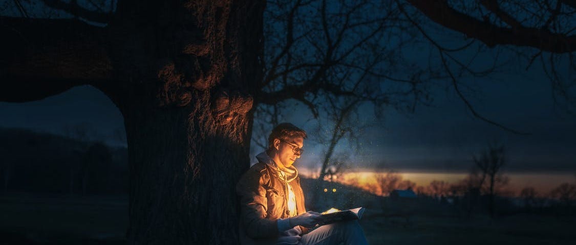 Man opening a magical book in the middle of a forest