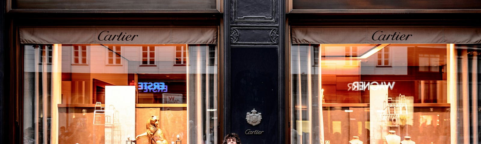 A young man playing the cello in front of a Cartier store