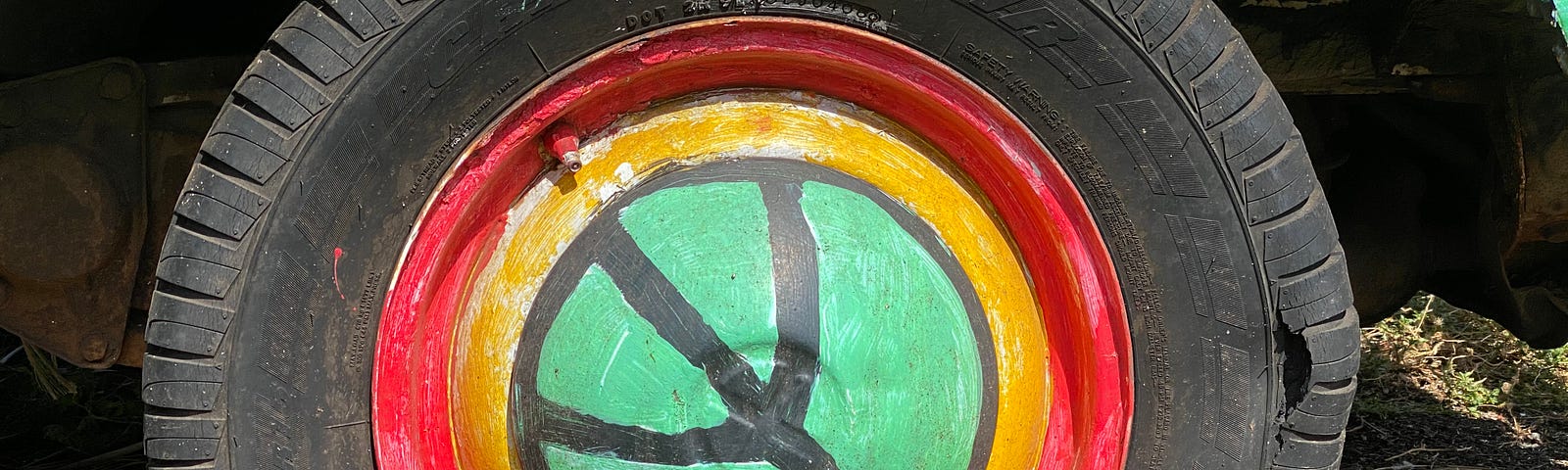 close up of flat tire with a peace sign painted on the hub cap