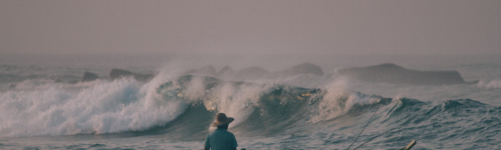 Here is a photo of a man fishing in a boat, battling the waves.